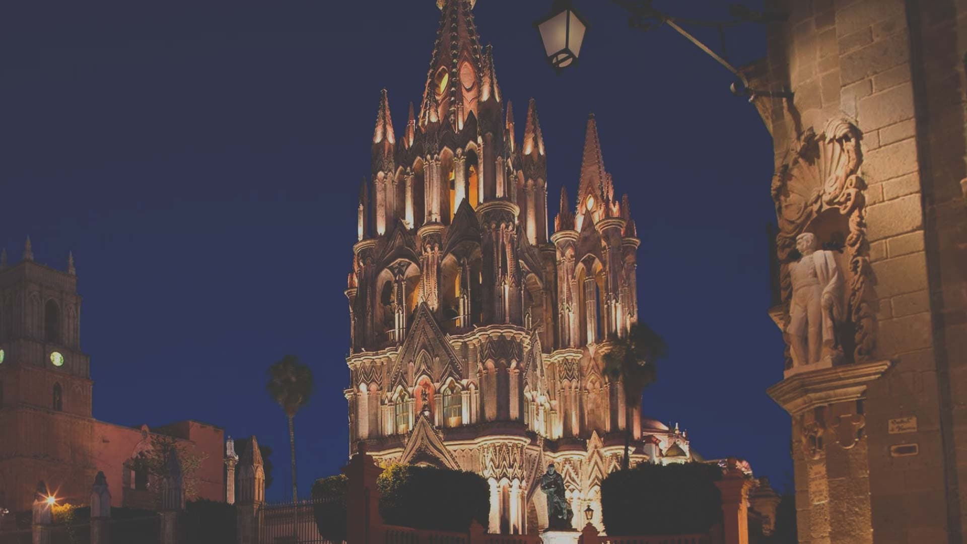 A San Miguel de Allende rooftop terrace at golden hour with the Parroquia in the background